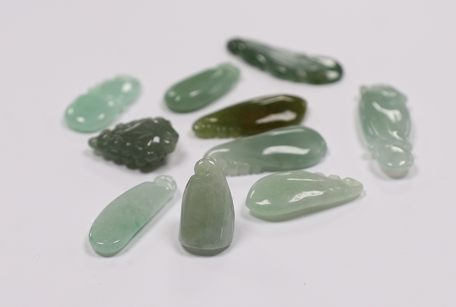 Ten various Chinese carved jadeite pendants